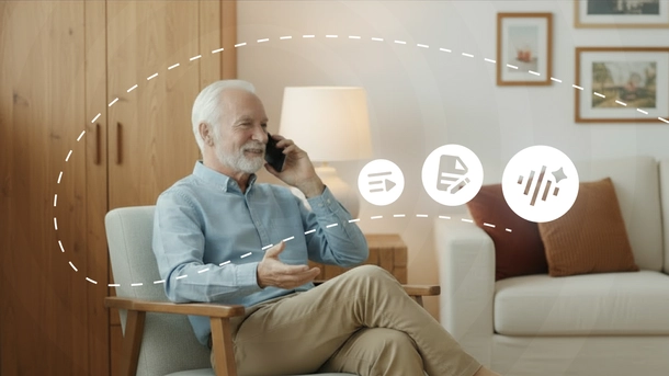 Starszy, zadowolony mężczyzna siedzi i rozmawia przez telefon komórkowy.